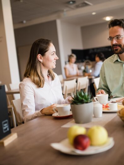 Two guests are having breakfast in the modern dining room with pastries, coffee, and juice. | © JUFA Hotels