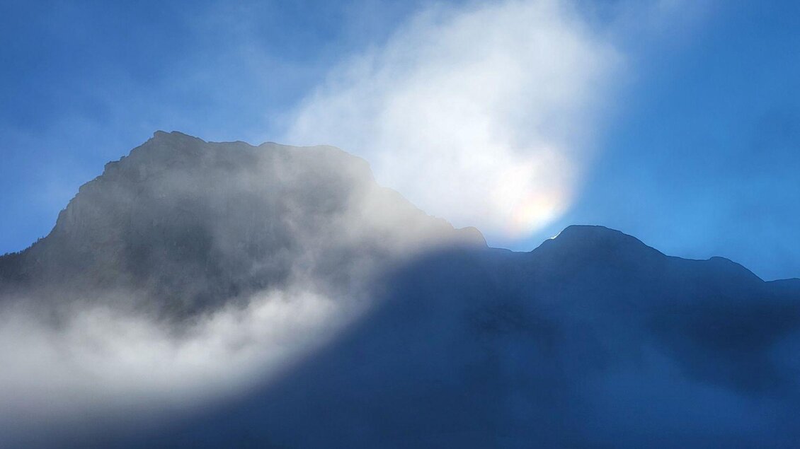 Ein majestätischer Berg, umhüllt von Nebel und Wolken. Der Himmel strahlt in einem klaren Blau. | © Petra Kirchschlager