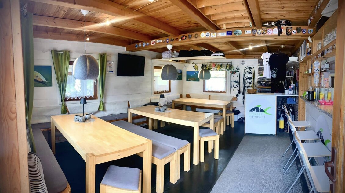 Eine gemütliche Innenansicht eines Restaurants mit Holztischen und Bänken. Die Wände sind dekoriert und es gibt eine freundliche Atmosphäre. | © Marschnig