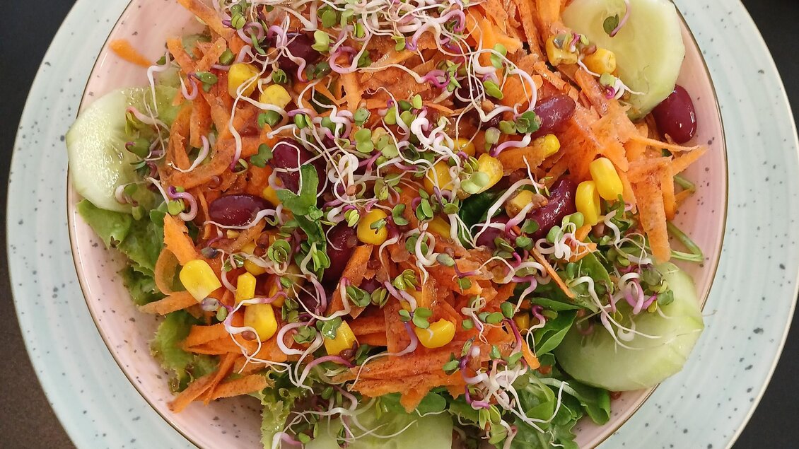 Ein bunter Salat mit frischen Gemüsekomponenten wie Karotten, Gurken und Sprossen. Die Mischung enthält auch Mais und Kidneybohnen. | © Sarah Windisch