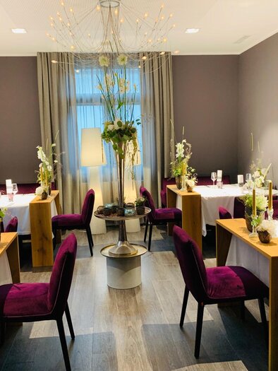 An elegant restaurant with tastefully set tables and stylish chairs. Soft lighting and decorative plants create an inviting atmosphere. | © Co:/mikejohann