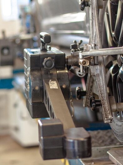 Eine Nahaufnahme eines Autos, das auf einer Werkbank steht. Im Bild ist ein Gerät zur Achsvermessung zu sehen, das an einem Reifen angebracht ist. | © Symbolfoto