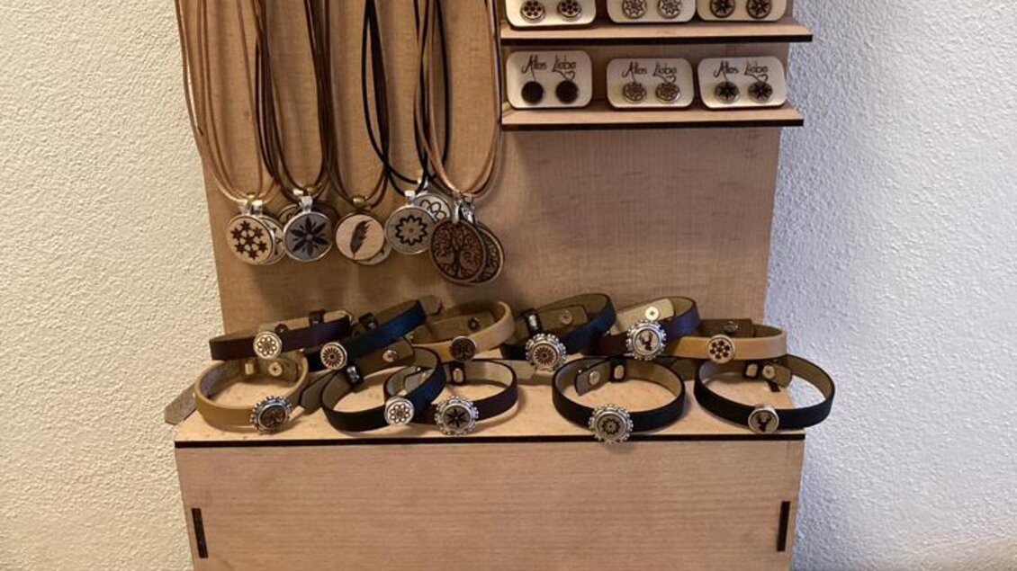 Eine Ausstellung von Schmuckstücken, einschließlich Halsketten, Armbändern und Ohrringen. Die Stücke sind auf einem Holzständer ordentlich angeordnet. | © KM Lasergravuren