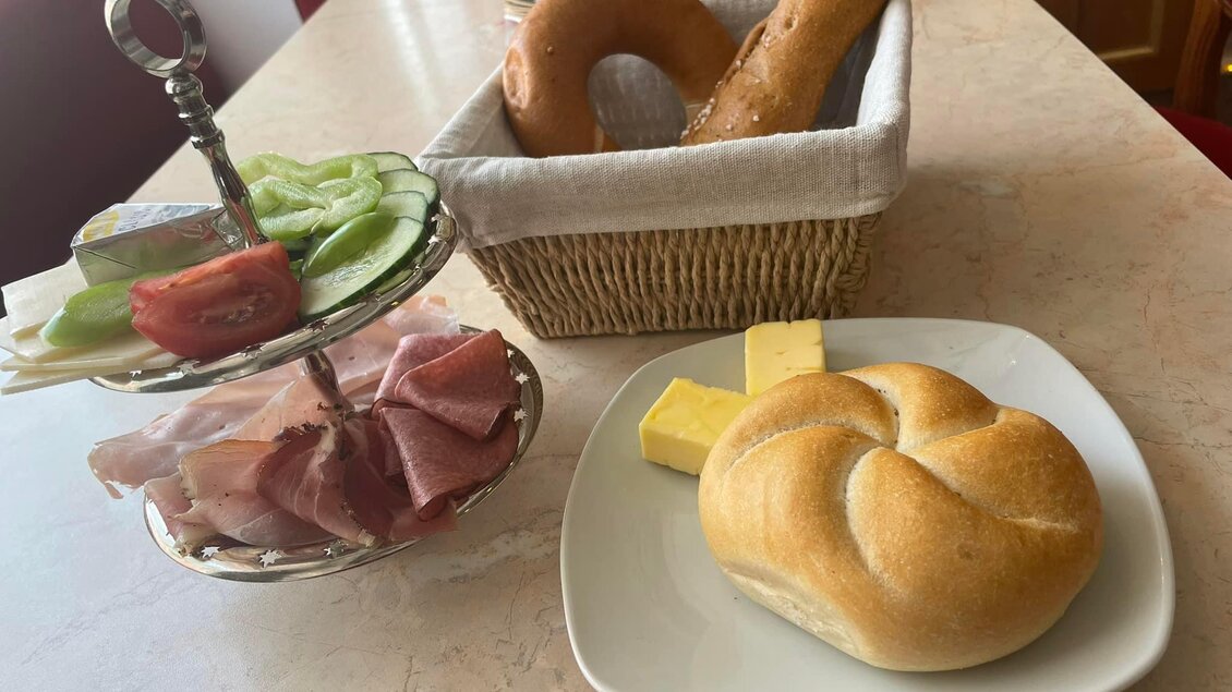 Ein reichhaltiges Frühstück mit verschiedenen Aufschnitt, frischem Gemüse und Brötchen. Dazu ein Korb mit Brezeln und Butter. | © Peer Dieter