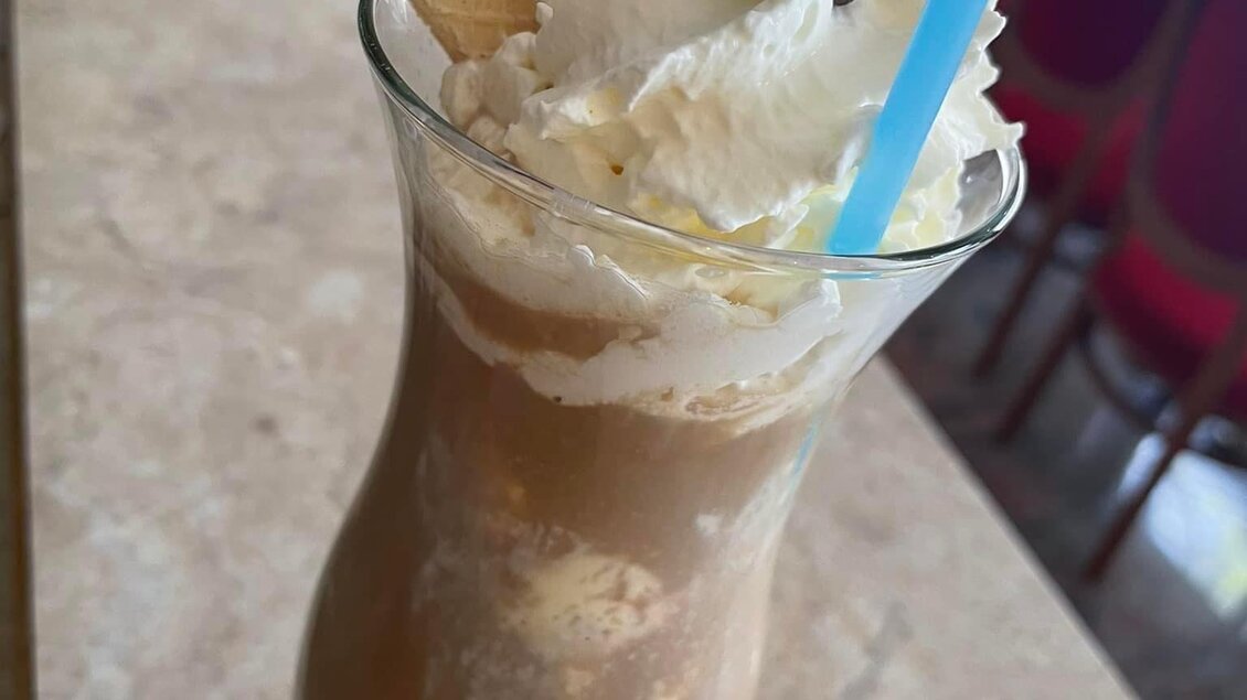 Ein leckerer Eiskaffee mit Sahne, zwei Waffeln und Kaffeebohnen als Dekoration. Der Drink befindet sich in einem eleganten Glas. | © Peer Dieter