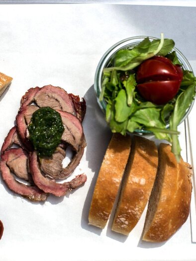 A plate with various foods, including meat, rolls, a fresh salad, and sweet potatoes. The arrangement is pleasingly served on white paper. | © Kaisers smoked BBQ