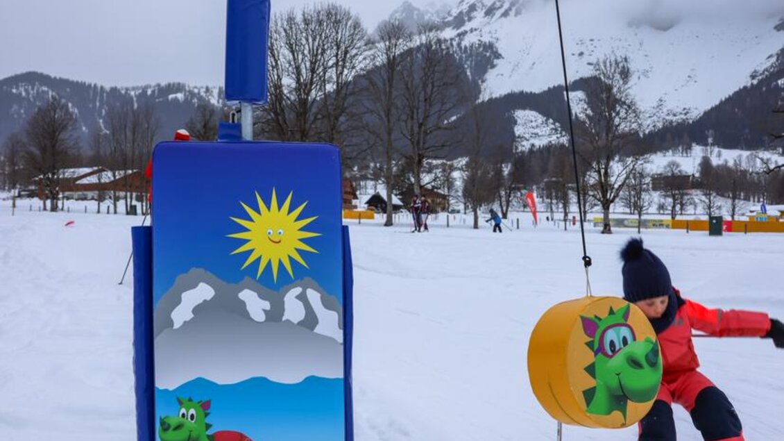 Ein Kind fährt Ski in einem schneebedeckten Gebiet. Im Hintergrund steht ein Skilift mit einem bunten Drachenmotiv. | © Loretta Kvitek