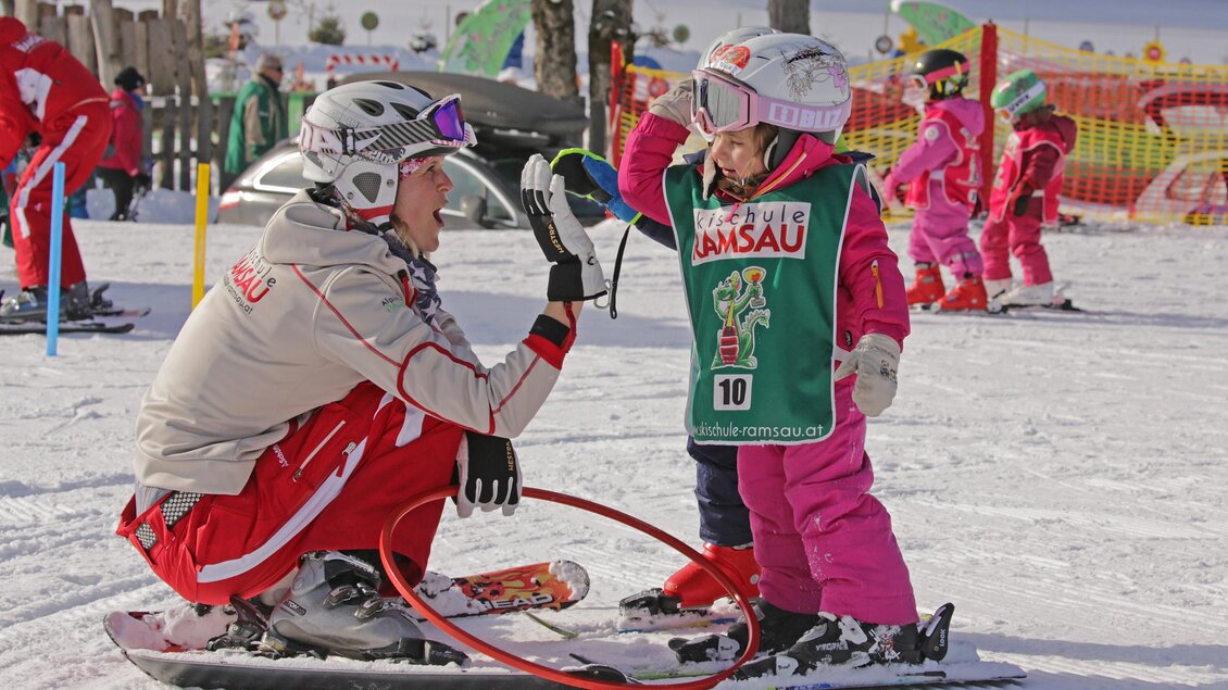 Ein Skilehrer und ein kleines Mädchen im Schnee. Beide haben Spaß beim Skifahren und tragen bunte Skikleidung. | © Hans-Peter Steiner