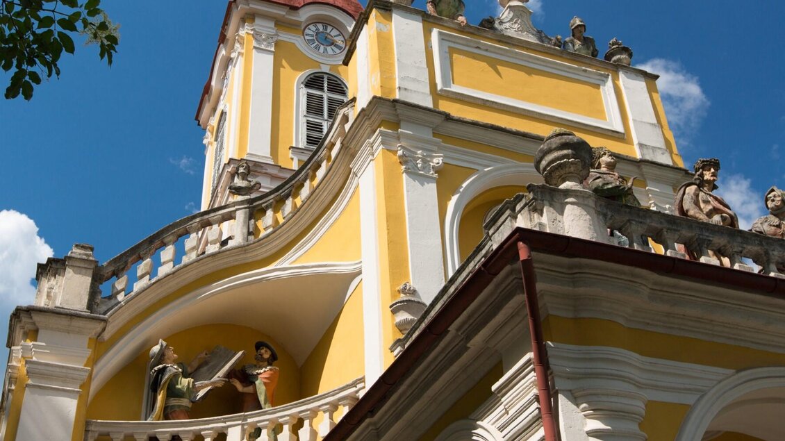 Gelbe Kalvarienbergkirche in Graz mit barockem Turm, Statuen und blauem Himmel im Hintergrund | © Graz Tourismus-Harry Schiffer
