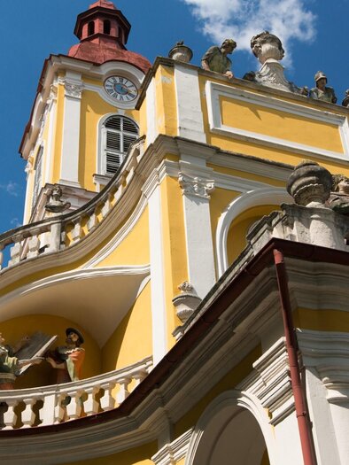 Gelbe Kalvarienbergkirche in Graz mit barockem Turm, Statuen und blauem Himmel im Hintergrund | © Graz Tourismus-Harry Schiffer
