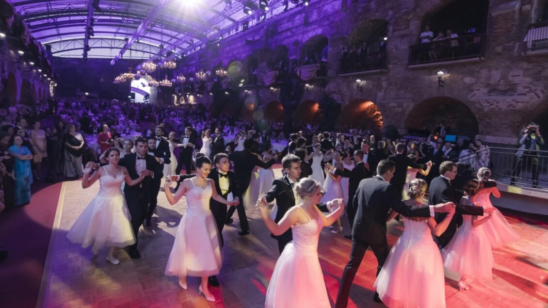 Eröffnungstanz mit Paaren in Ballkleidern und Anzügen auf dem Ball in der Kasemattenbühne Graz unter festlicher Beleuchtung | © Marija Kanizaj