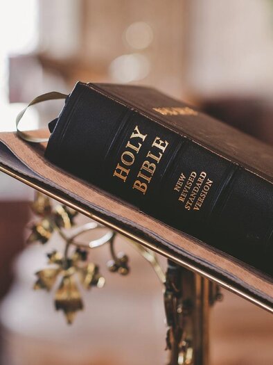 An open Bible is on a lectern. The book has an elegant black cover and is placed in a beautiful setting. | © Symbolbild PixaBay