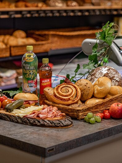 A table with various foods, including bread, cold cuts, fruit, and beverages. The presentation is attractive and inviting. | © Christine Höflehner