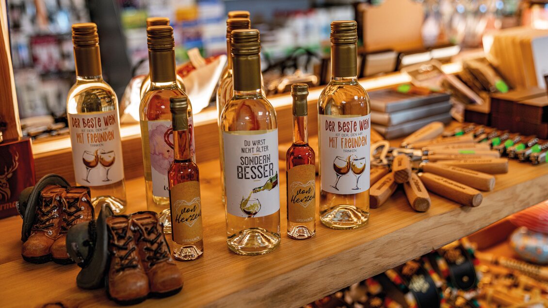 Eine Auswahl an Flaschen mit alkoholischen Getränken auf einem Holzregal. Im Hintergrund sind weitere Produkte und Farben zu sehen. | © Christine Höflehner