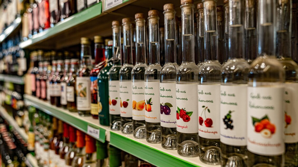 Regale mit verschiedenen Flaschen alkoholischer Getränke in einem Geschäft. Die Flaschen sind sortiert und haben Etiketten mit bunten Früchten. | © Christine Höflehner