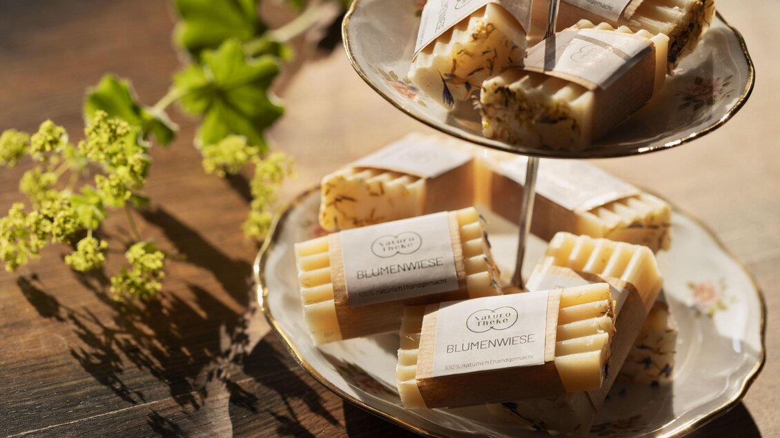 Hübsch arrangierte Seifen auf einem eleganten zweistöckigen Teller. Die Seifen sind mit einem natürlichen Design und Etiketten versehen. | © Sloho Bergurlaub