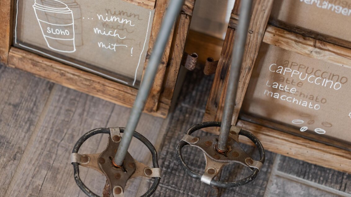 Zwei Mischstäbe aus Metall stehen neben handgeschriebenen Tafeln. Die Tafel zeigt Getränkeangebote in einer gemütlichen Café-Umgebung. | © Sloho Bergurlaub