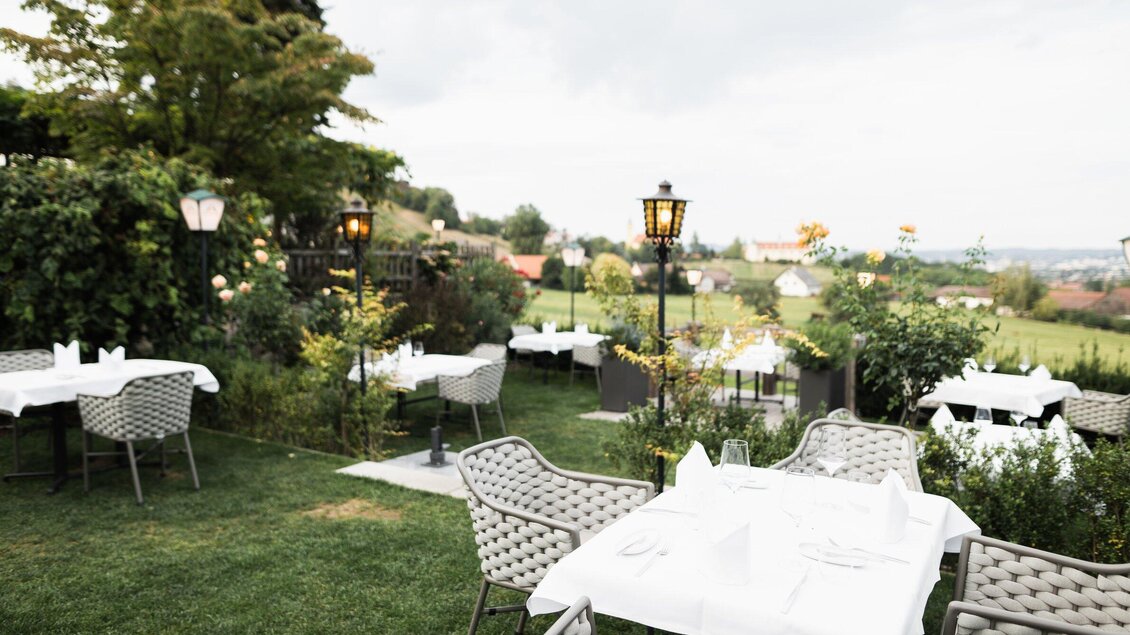 Ein einladender Außenbereich eines Restaurants mit eleganten Tischen und Stühlen. Umgeben von grünen Pflanzen und einer malerischen Aussicht. | © Kehlberghof