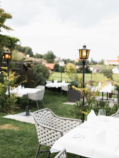 Ein einladender Außenbereich eines Restaurants mit eleganten Tischen und Stühlen. Umgeben von grünen Pflanzen und einer malerischen Aussicht. | © Kehlberghof