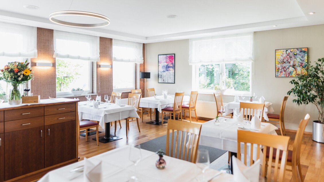 Ein elegantes Restaurant mit hellen Tönen und gut eingedeckten Tischen. Große Fenster sorgen für viel Tageslicht und eine einladende Atmosphäre. | © Kehlberghof