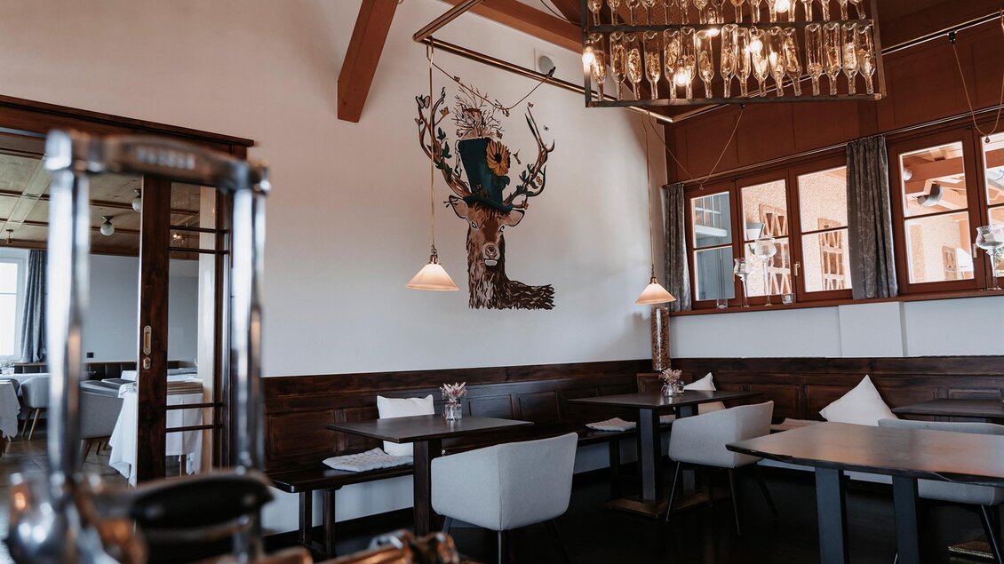 Ein stilvolles Restaurant mit Holzdekor und gemütlichen Tischen. Eine elegante Beleuchtung und eine dekorative Wandgestaltung schaffen eine einladende Atmosphäre. | © Jaglhof