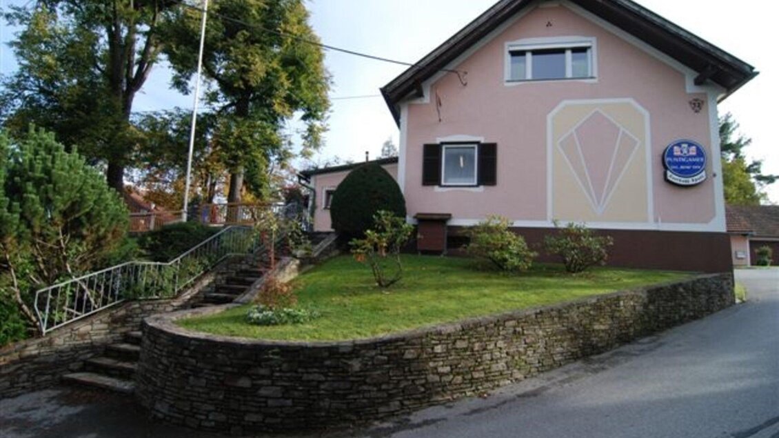 Ein charmantes Haus mit einer pinken Fassade und einem gepflegten Vorgarten. Der Eingang ist von einer niedrigen Mauer und einer Treppe umgeben. | © Fam. Fauland
