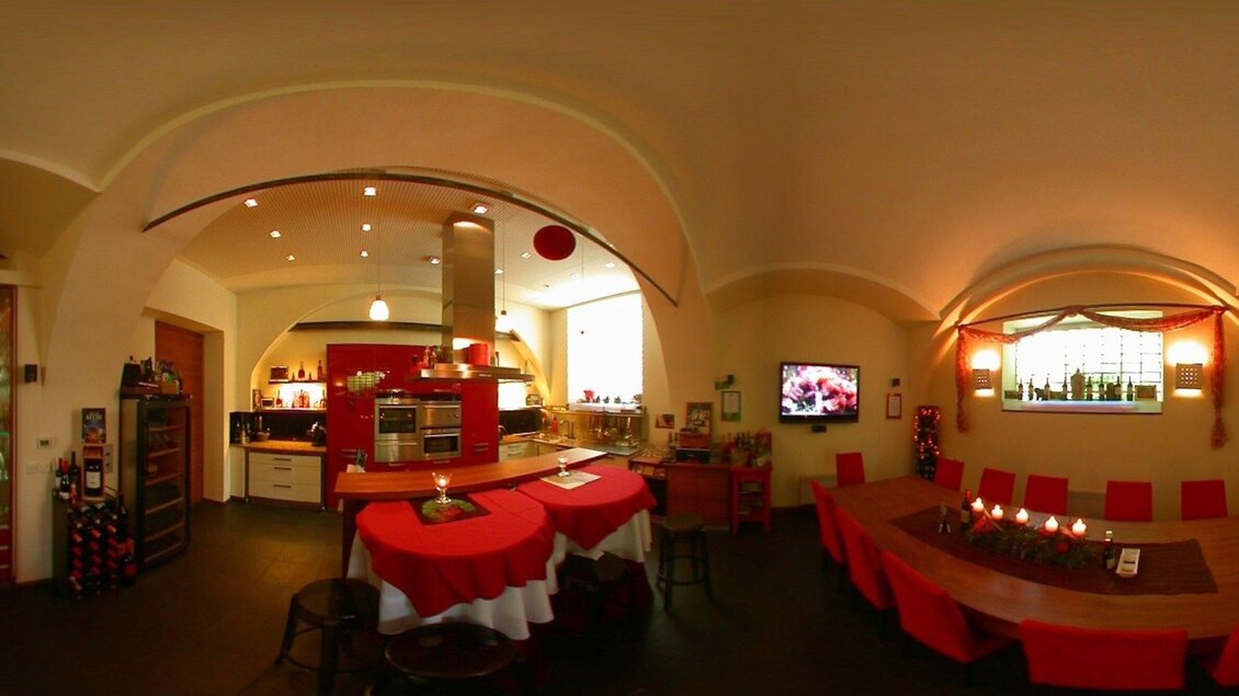 Eine moderne Küche mit roten Akzenten und einer großen Essgruppe. Der Raum ist gut beleuchtet und bietet eine einladende Atmosphäre. | © Kitchen12