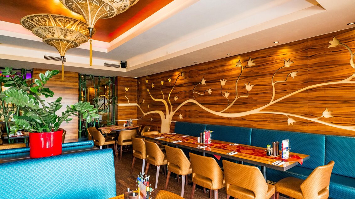 Ein stilvolles Restaurant mit gemütlichen Sitzplätzen und einer Holzdekor-Wand. Die Beleuchtung schafft eine einladende Atmosphäre. | © Region Graz - Mias Photoart