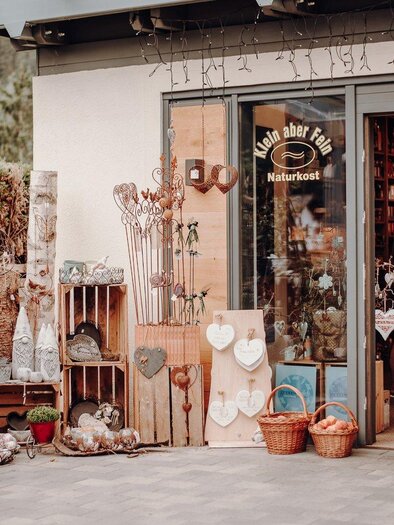 An inviting shop with handmade goods and natural products. The entrance area is lovingly decorated with various baskets and decorative items. | © GenussReich