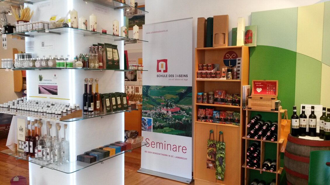 Ein gut sortierter Verkaufsraum mit verschiedenen Flaschen und Produkten. Im Hintergrund steht ein Banner mit Informationen zu Seminaren. | © Benediktinerstift St. Lambrecht