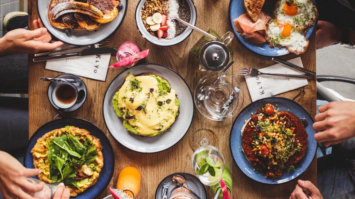 Ein schöner Tisch mit verschiedenen Gerichten, darunter Omelett, Salat und Nachspeisen. Getränke und Besteck sind ebenfalls auf dem Tisch zu sehen. | © Klyo - Aaron Jiang