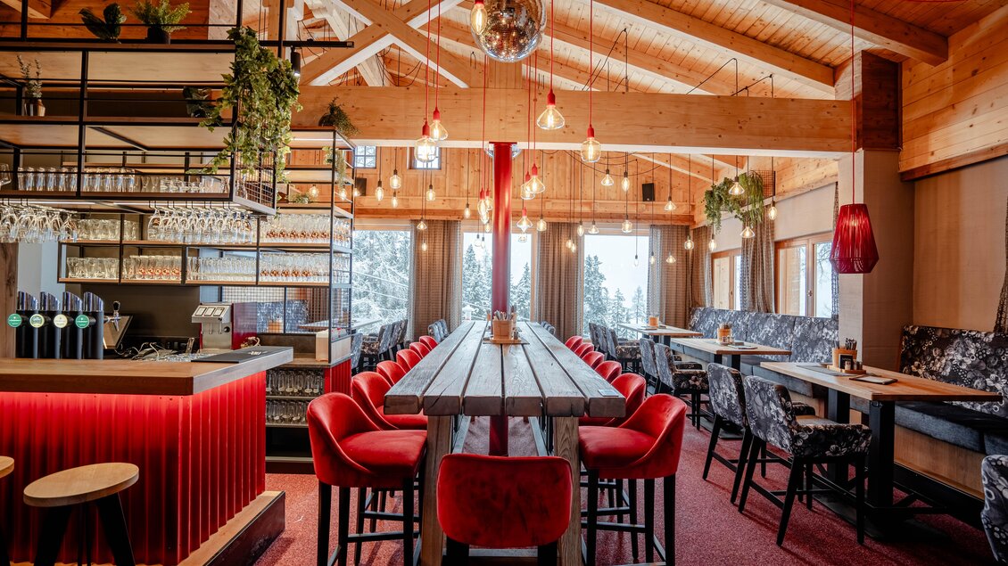 Ein modernes Restaurant mit Holzdekor und einer einladenden Atmosphäre. Große Fenster bieten einen Blick auf die verschneite Landschaft. | © Knapplhütte