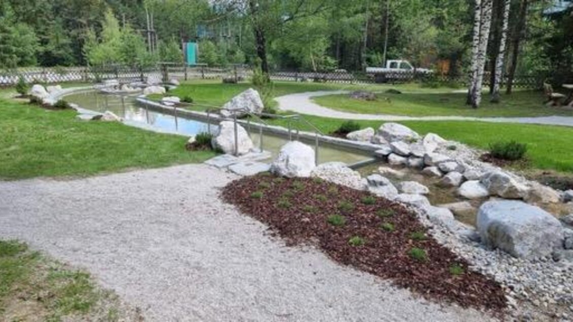 Ein ruhiger Park mit einem kleinen Wasserlauf und glatten Steinansammlungen. Grüne Wiesen und Bäume umgeben die Wege. | © Marktgemeinde Gröbming