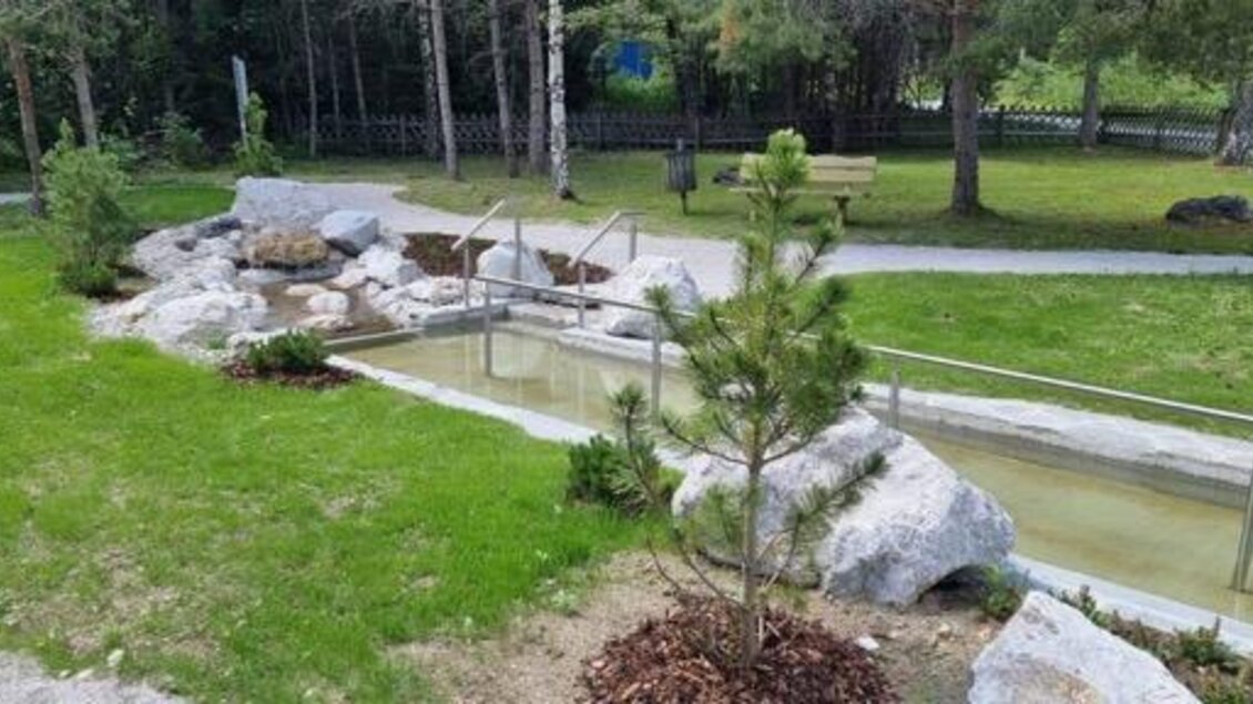 Ein ruhiger Park mit einem fließenden Wasserlauf und Steinen. Umgeben von Bäumen und einem gepflegten Rasen. | © Marktgemeinde Gröbming