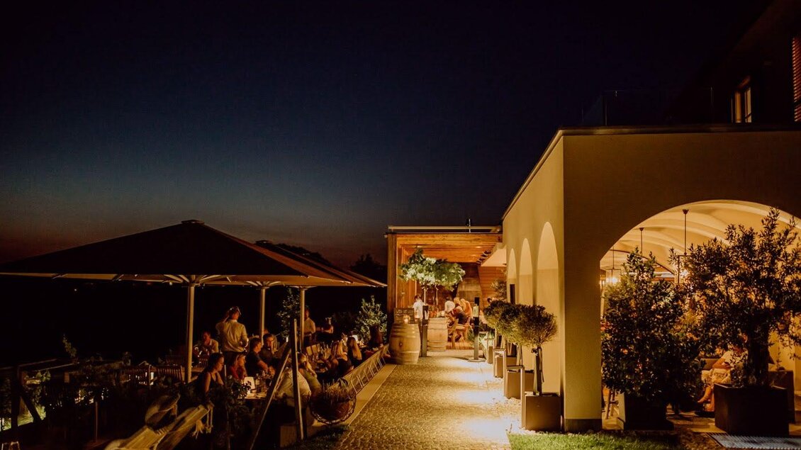 Ein einladendes Restaurant im Freien bei Nacht, beleuchtet von warmem Licht. Gäste sitzen gemütlich unter einem Pavillon und genießen die Atmosphäre. | © Kogel 3