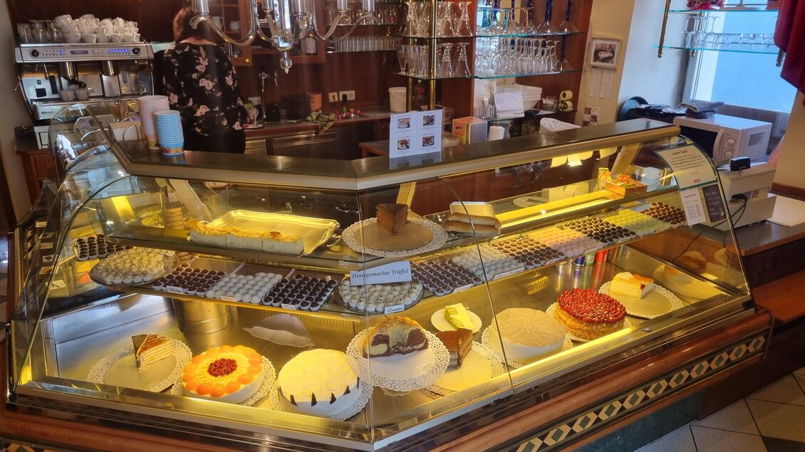 Eine gemütliche Konditorei mit einer Vitrine voller köstlicher Torten und Desserts. Im Hintergrund ist eine Bedienung zu sehen. | © Erlebnisregion Murtal