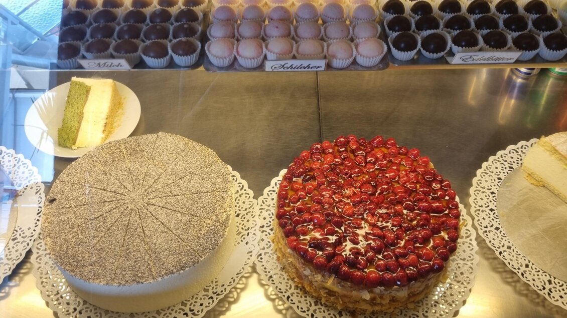 Eine Auslage mit verschiedenen köstlichen Torten und Desserts. Dazu gehören eine Erdbeertorte, eine Sahnetorte und eine Auswahl an Macarons. | © Erlebnisregion Murtal