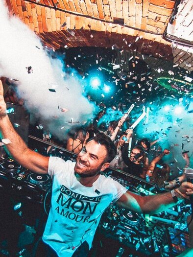 A vibrant party scene with dancing people and colorful confetti. The atmosphere is energized and festive. | © Kottulinsky