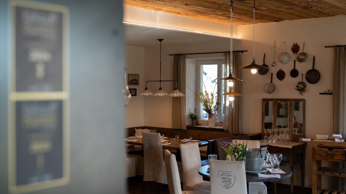 Gemütlicher Gastraum mit Holzelementen und dekorativer Wandgestaltung im Wirtshaus Kreuzwirt. | © MatthiasSchweyer