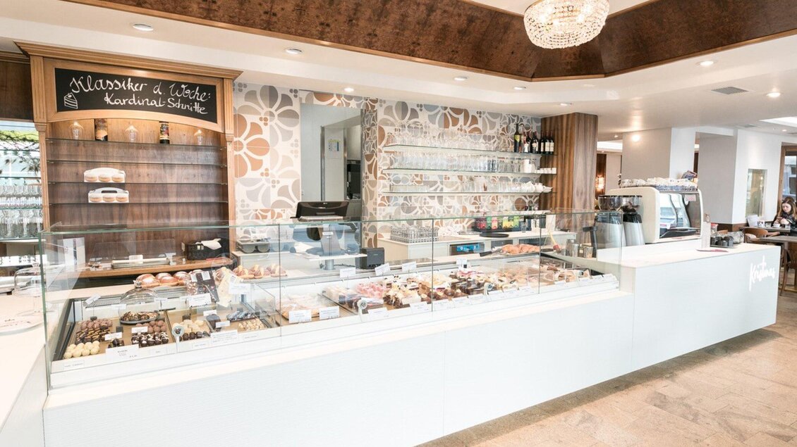 Ein elegantes Café mit einer modernen Theke voller Süßigkeiten und Desserts. Die gemütliche Atmosphäre lädt zum Verweilen ein. | © Harald Tauderer und Michaela Begsteiger
