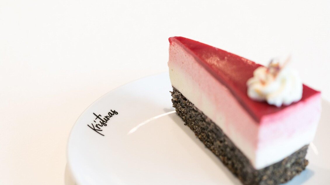 Ein Stück bunter Torte auf einem weißen Teller. Die Torte hat mehrere Schichten in Rosa, Weiß und Schwarz. | © Harald Tauderer und Michaela Begsteiger