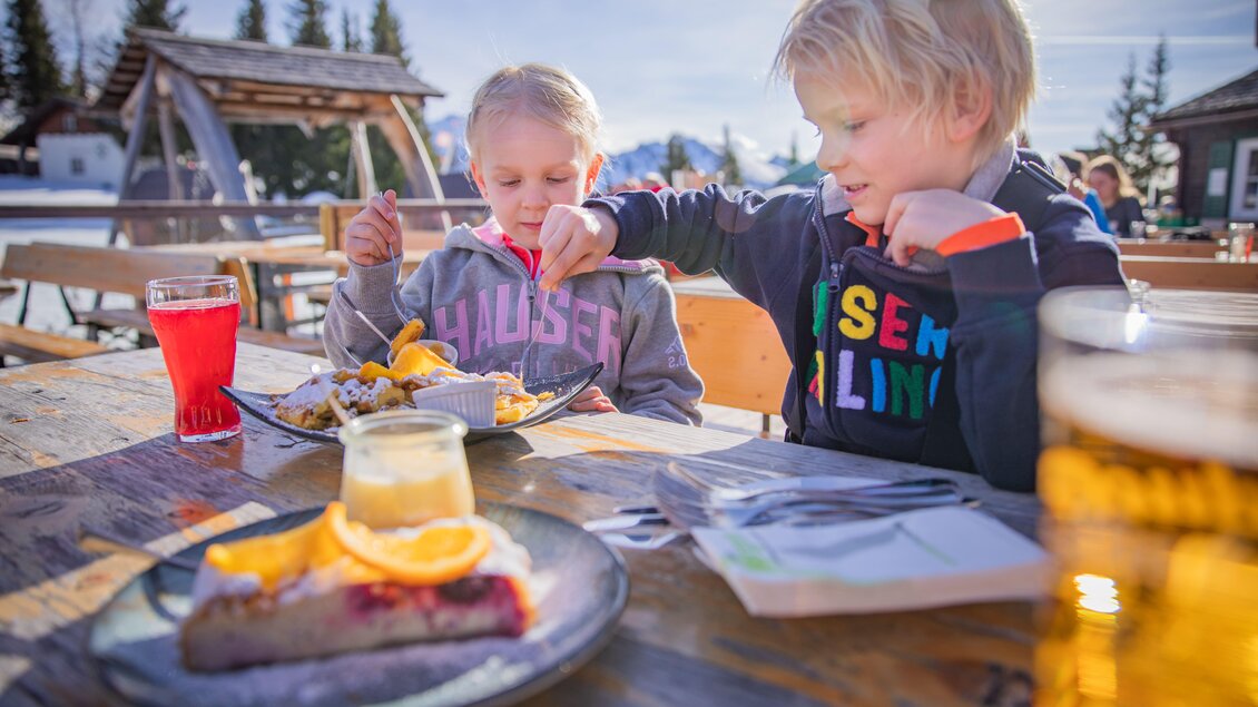 Zwei Kinder essen süße Nachspeisen und Kuchen auf der Sonnenterrasse der Krummholzhütte. | © Krummholzhütte