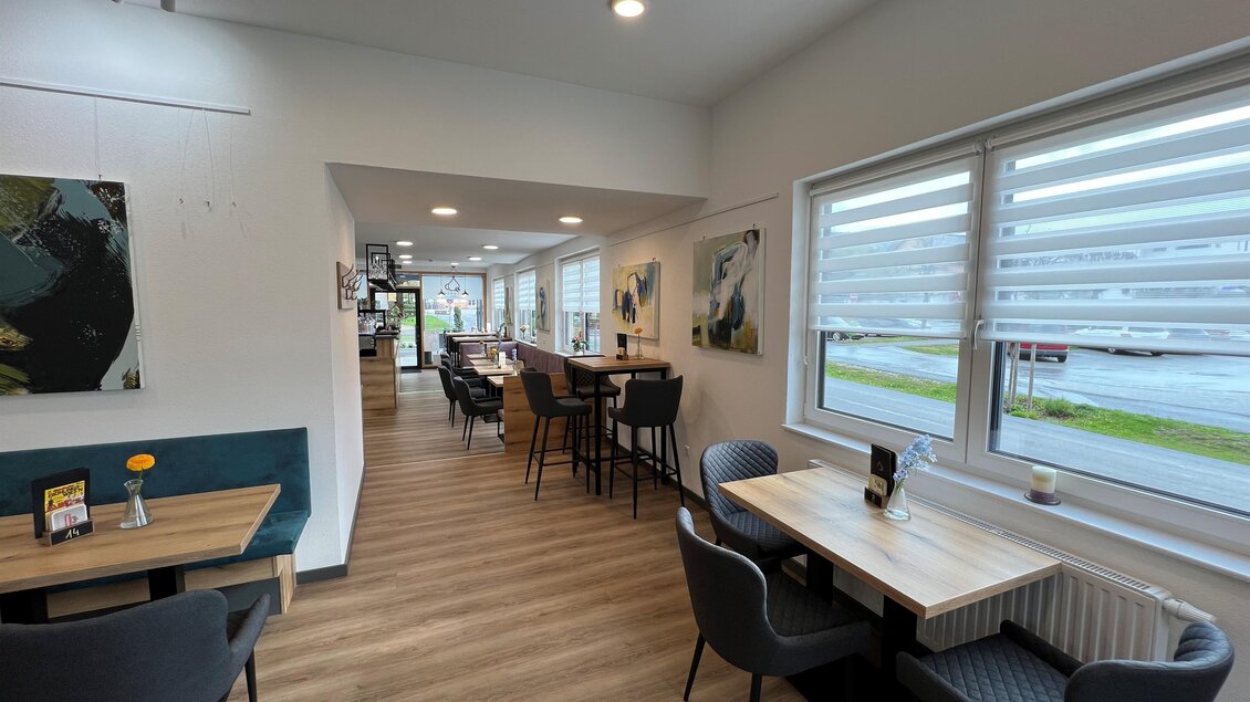 Ein modernes Café mit hellen Wänden und Holzfußboden. Es gibt Tische und Stühle sowie große Fenster, die viel Tageslicht hereinlassen. | © Andreas Albrecher