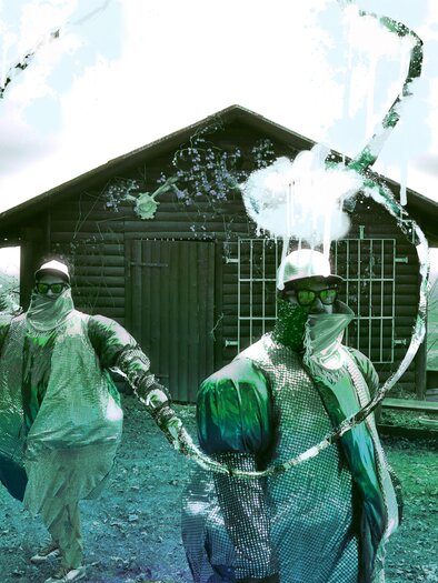 Zwei Personen in Schutzanzügen stehen vor einer Stube in der Natur. Sie scheinen Wasser oder Flüssigkeit zu spritzen, umgeben von einer malerischen Landschaft. | © itshe+io