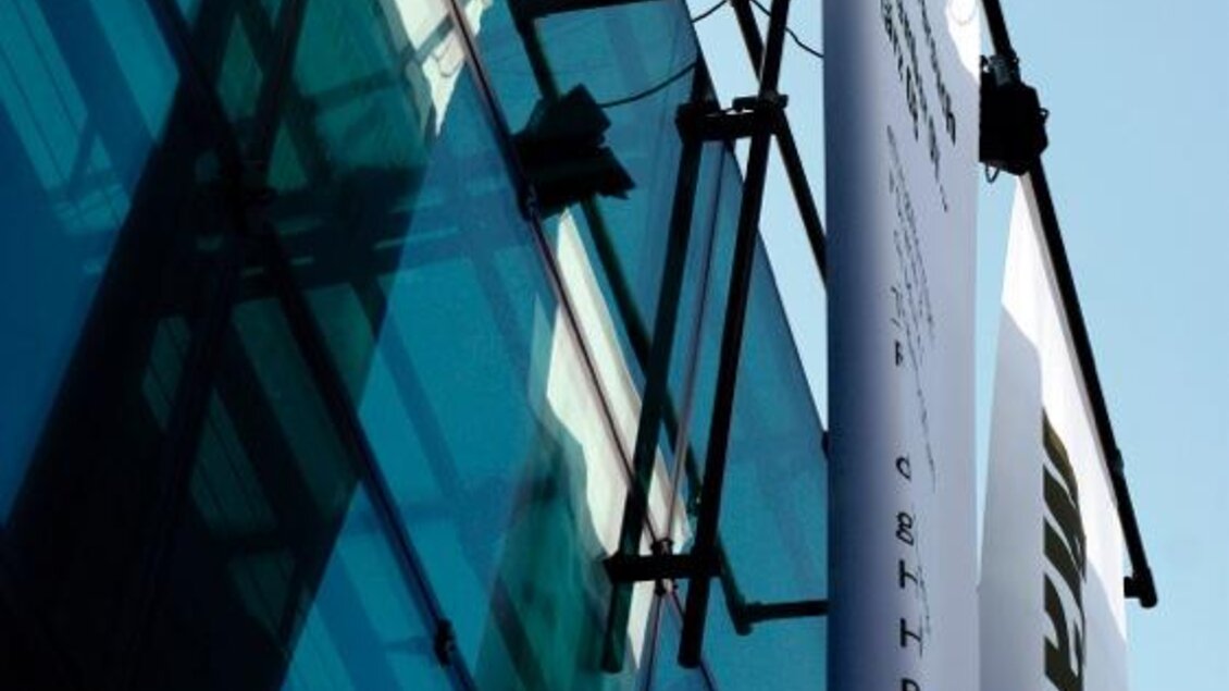 Ein modernes Gebäude mit großen Glasfenstern. An der Fassade hängt ein großes Werbebanner. | © Martin Lotter