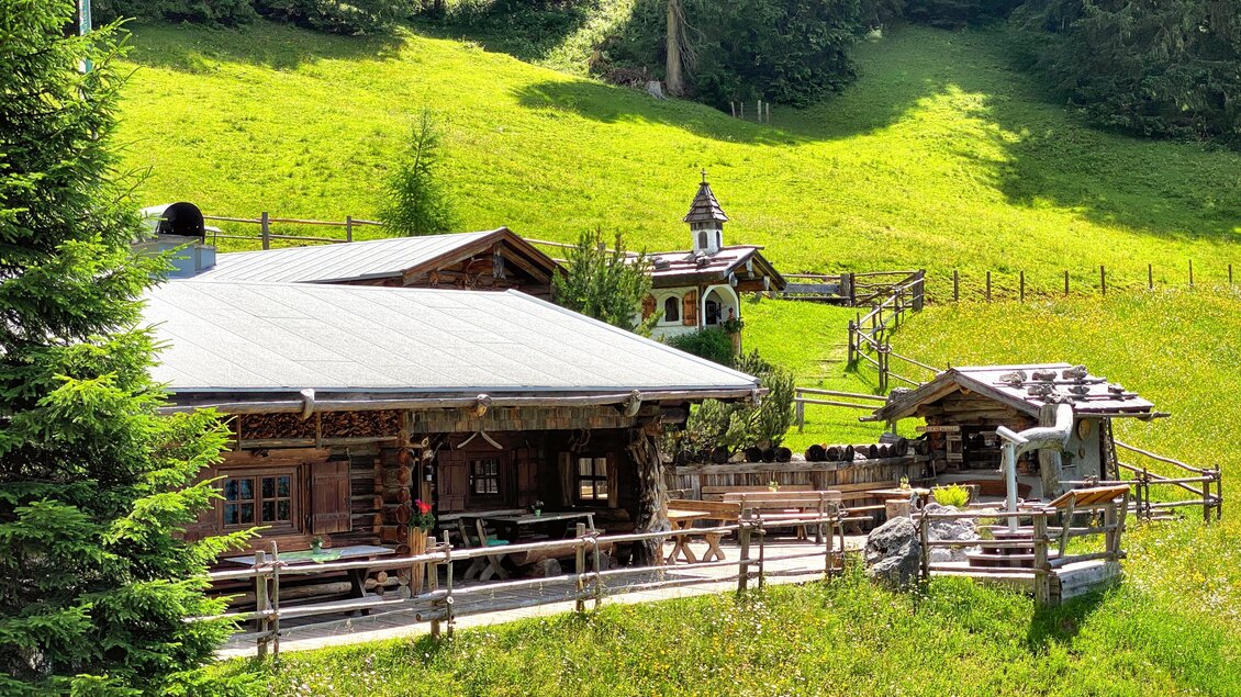 Eine idyllische Berghütte umgeben von grünen Wiesen und Bäumen. Die Holzstruktur fügt sich harmonisch in die natürliche Umgebung ein. | © ©KajetanGerharter 