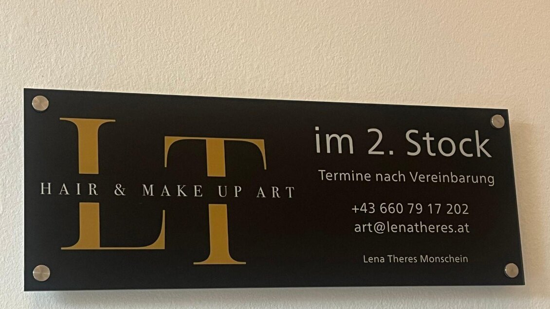 Ein dekoratives Schild für einen Friseur- und Makeup-Service im zweiten Stock. Es enthält Kontaktdaten und den Namen der Inhaberin, Lena Theres Monschein. | © TVB Ausseerland- Salzkammergut_Nathalie Schröttenhamer