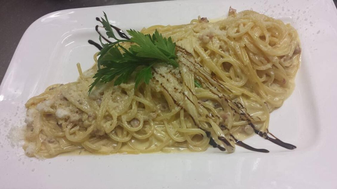 Ein Teller Spaghetti mit einer cremigen Sauce und Käse. Frische Kräuter garnieren das Gericht. | © La Piazzetta