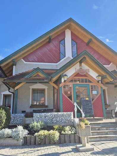 Ein modernes Haus mit buntem Dach und einer einladenden Eingangstür. Der Eingangsbereich ist mit Blumen und Pflanzen dekoriert. | © Tourismusverband Murau