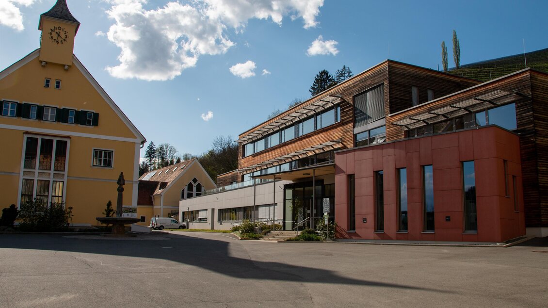 Eine moderne Architektur vereint sich mit traditionellem Stil in dieser bildschönen Landschaft. Im Vordergrund stehen ein klassisches gelbes Gebäude und ein zeitgenössisches Design in Holz und rot. | © @ Siilberberg